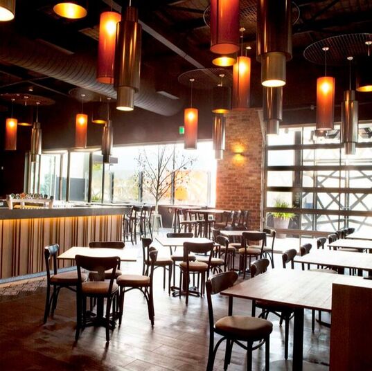 photo of inside of Perth bar with warm orange hanging lights from ceiling, wooden tables and chairs set all around